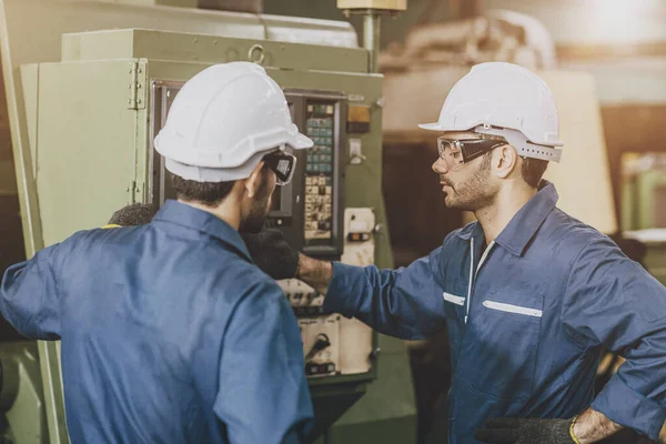 Engineer mechanic team staff worker training operate lathe milling CNC machine in metal factory.