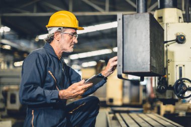 Kıdemli yaşlı mühendis yüksek beceri otomatik CNC torna makinesini otomasyon fabrikasında çalıştır.
