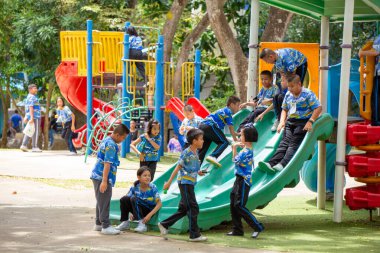 Bangkok, Tayland-26 Haziran 2023: Bir grup şirin çocuk okul parkında oyun parkı malzemeleriyle eğleniyor.