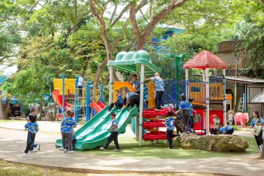 Bangkok, Tayland-26 Haziran 2023: Bir grup şirin çocuk okul parkında oyun parkı malzemeleriyle eğleniyor.