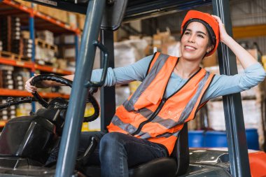 Mutlu genç depo çalışanı fabrika envanter nakliye ürünlerini yükleme kontrolü için forklift sürücüsüne gülümsemenin keyfini çıkar.