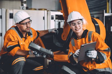 Modern otomasyon fabrikasında çalışan mutlu mühendis ekibi robot kol kontrol eğitim operasyonu ile çalışıyor. kadın işçi makine öğrenme endüstrisi