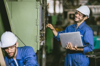Mühendis kadro çalışanı arkadaş gülerek birlikte ağır metal endüstrisi çelik torna fabrikasında çalışıyoruz.