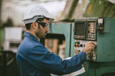 Latin kökenli Hintli erkek işçi kontrolü CNC makinesini heavy metal fabrikasında çalıştırıyor.
