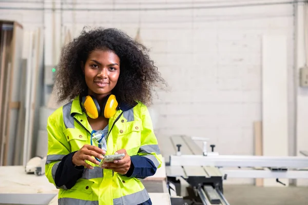 stock image portrait black african woman smart young engineer worker with safty protection equipments happy smiling with smartphone at wood furniture factory