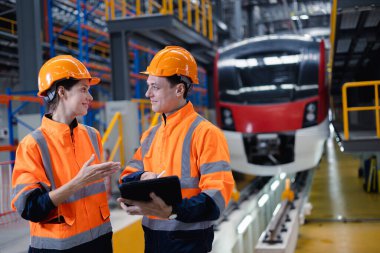 Mühendis adam ve kadın işçi ekibi birlikte elektrik tren istasyonu nakliye fabrikası fabrikası teknisyen kadrosunda çalışıyor..