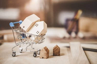 Alış veriş arabasındaki küçük ahşap ev modeli. Kiralık ev kiralama, yeni konaklama konsepti satın al..