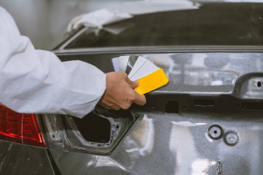 araba gövdesi boyacısı boya renklerini otomobil garajı kaporta atölyesindeki renk tonunu seçmek için örnek kart kullanarak seçer