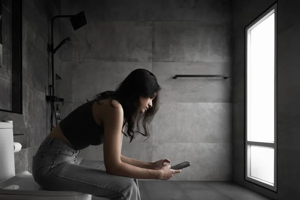 stock image Hikikomori Syndrome in teenager. Young Introvert woman living alone in bathroom using smart phone social escape people