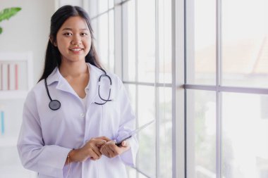 Genç Asyalı doktor rolü. Okul laboratuarında gülümseyen ve mesaj atacak yeri olan mutlu bir doktor.