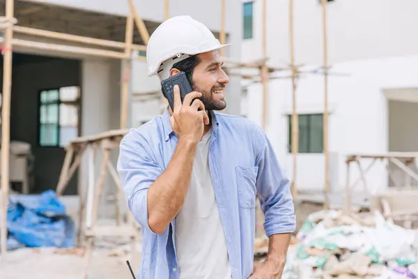 happy foreman builder using smart phone calling business contact in construction site. construction engineer or architect with modern connection technology device.real estate investor