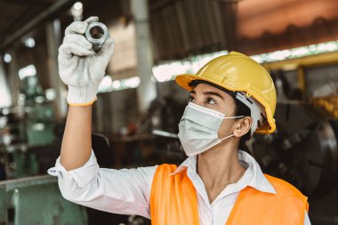 Ağır metal makinesiyle çalışan genç Asyalı kadın işçi değirmen fabrikası sanayii hijyen için kirli işyeri koruyucu yüz maskesi.