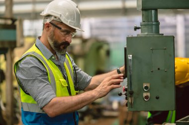 Kıdemli İspanyol mühendis erkek uzman işçi ağır sanayi fabrikasında metal torna makinesi kullanıyor.