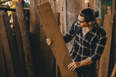 Katılımcı mobilya üreticisi yeni projeler için uygun ahşap parçası bulmak için odun yığınından malzeme seçin.