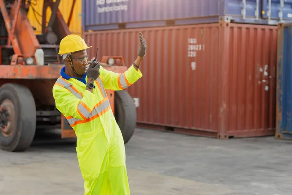 African male dock worker control loading containers cargo at warehouse container shipyard. Marine and carrier staff employee. cargo loading operator shipping export logistics ship yard.