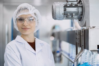 Portre mutlu kadın işçi hijyen fabrikasında çalışıyor. Temiz bir çizgide su içiyor. Evcil hayvan plastik şişesi üretimi.