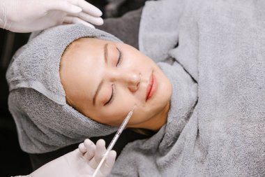 Yüz gerdirme için kadın iğnesi doldurucu yüz bakımı kliniğindeki kırışıklıkları temizler.
