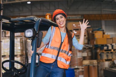 Mutlu kadın forklift çalışanı depo lojistiğinde kargo ürünleri depolama endüstrisinde çalışıyor.