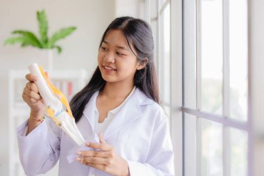 Genç Asyalı doktor rolü. Okul laboratuarında gülümseyen ve mesaj atacak yeri olan mutlu bir doktor.