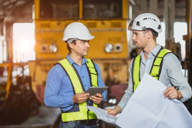 Mühendis takımı zeki genç beceri işçisi danışman danışman danışmanı lokomotif tren deposu atölyesinde tasarım katı planıyla birlikte çalışıyor.
