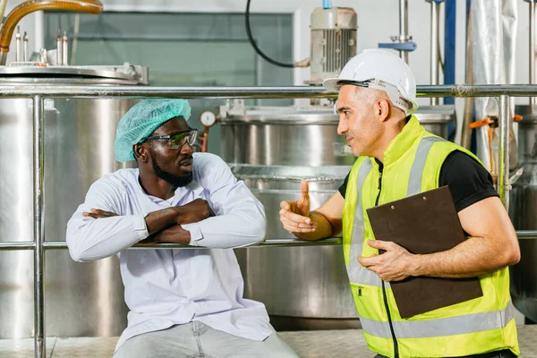 Engineer safety manager worker talking discussion with friend production line worker in food and drink factory