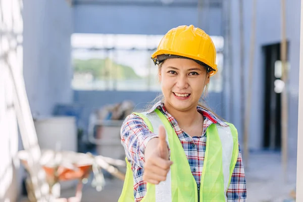 Asian woman construction worker happy smiling thumbs up at building construction site background