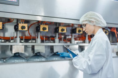 Su fabrikasında çalışan beyaz kadın işçiler içme suyu içme makinesi hattının şişelenmesinde temiz hijyen sürecinde.