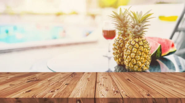blur tropical fruit drink on pool side table in beach hotel resort with blank wooden counter for summer season travel products montage background