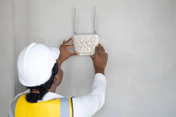 Professional network engineer installation indoor room home networking system hand placing wifi router wireless access point internet connection setup at the wall.