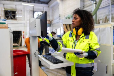 Afrikalı siyahi kadın işçiler ahşap kesici makine mobilya fabrikası ve güvenlik kıyafeti ile çalışıyorlar.