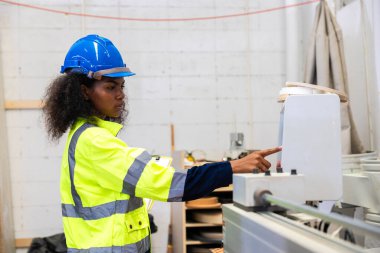 Afrikalı siyahi kadın işçiler ahşap kesici makine mobilya fabrikası ve güvenlik kıyafeti ile çalışıyorlar.