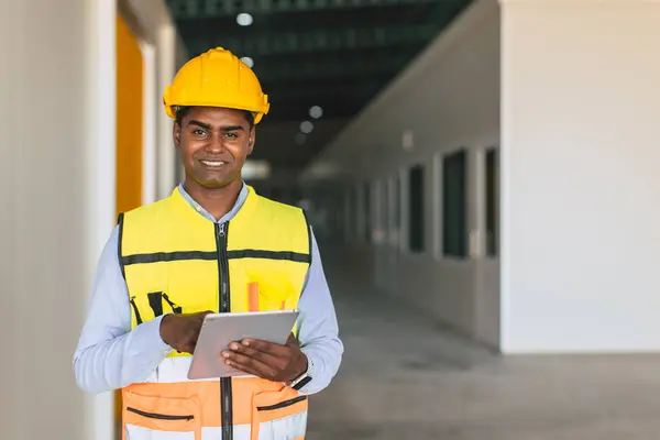 portrait indian engineer forman staff worker standing happy smiling in cargo factory indoor with tablet