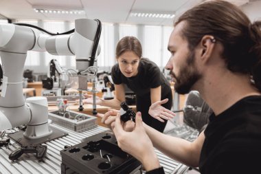 Endüstriyel Robotik Programı üniversite öğrencileri mühendislik laboratuvarı sınıfında robot robot kolu simülasyonu modeli ile eğitim mekanik birleşimi öğreniyor..