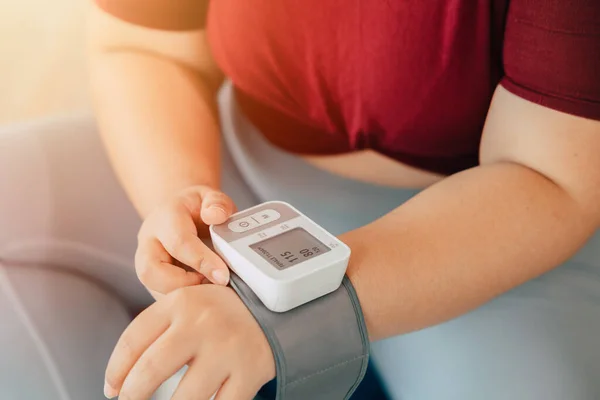 fat women measuring blood pressure using wrist blood vessels monitor modern home medical equipment