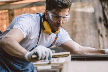 Marangoz adam ahşap atölyede ahşap mobilya yapmak için el işi ustalığı ile uğraşır..