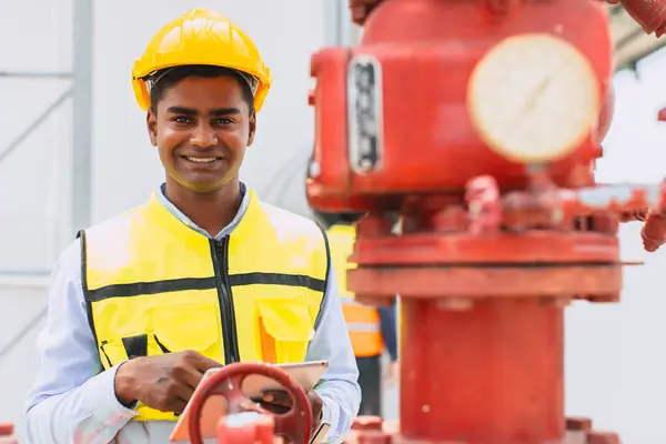 portrait happy indian engineer safety staff worker work control operate valve gas pipe oil industry