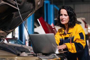 Otomobil araba mühendisi ECU tanılama ayarı kullanan dizüstü bilgisayar kullanıyor. Otomatik servis garajında motor sorunu var.