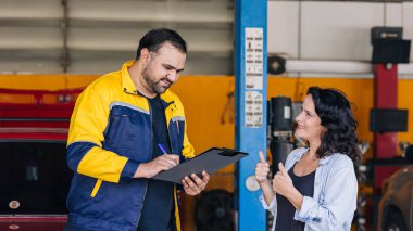 Müşteri bayanları otomobil merkezi atölyesinde tamirci araç servisi denetim listesinin keyfini çıkarıyorlar.