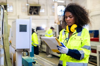 Afrikalı siyahi kadın işçiler ahşap kesici makine mobilya fabrikası ve güvenlik kıyafeti ile çalışıyorlar.