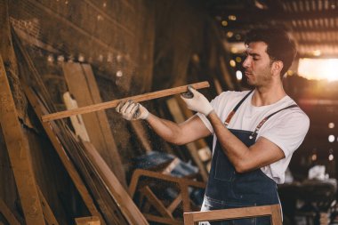 Marangoz adam ahşap atölyede ahşap mobilya yapmak için el işi ustalığı ile uğraşır..
