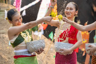 Songkran festivali. Geleneksel giysiler içinde Kuzey Taylandlılar Songkran kültür festivalinde kum pagodası ve renkli kağıt bayrak ile birlikte su sıçratıyor..