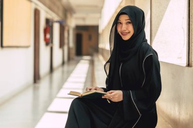 Müslüman niqab kadın Kuran 'ı ve Kutsal El-Kur' an 'ı okuyup öğreniyor. Arap Suudi siyah çarşaflı kadın.