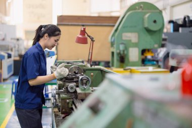 Asyalı kadın işçiler çelik fabrikasında CNC torna makinesinde çalışıyor.
