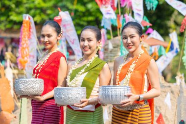 Songkran festivali. Geleneksel giyinmiş Kuzey Taylandlı insanların portresi Songkran 'ın yaz günü Tayland kültür festivalinde el yapımı gümüş kase kullanılıyor..