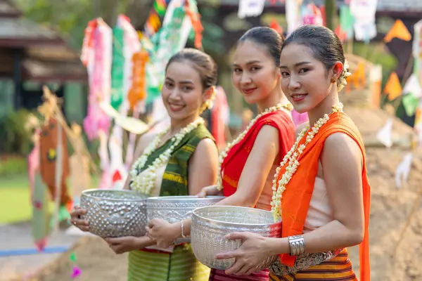 Songkran festivali. Geleneksel giyinmiş Kuzey Taylandlı insanların portresi Songkran 'ın yaz günü Tayland kültür festivalinde el yapımı gümüş kase kullanılıyor..