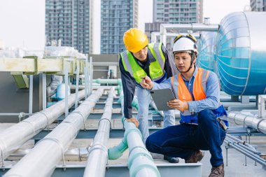Mühendis ekip çalışması teknisyenleri otel kazan tankı sıcak su boru sistemi hizmeti veriyor. Ekip, çatıdaki su taşıma hattını kontrol ediyor..