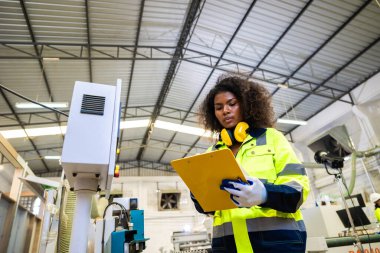 Afrikalı siyahi kadın işçiler ahşap kesici makine mobilya fabrikası ve güvenlik kıyafeti ile çalışıyorlar.