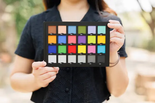 正確な色の写真やビデオを校正するためのカラーチェッカーボードまたはカラーチャートを保持する写真モデル ストック画像