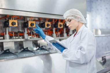 Kadın işçiler içme suyu fabrikasında çalışıyor. Kaliteli içme suyu doldurma makinesini kontrol ediyorlar.