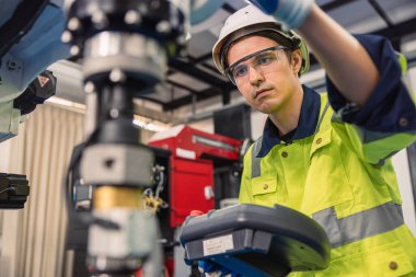 Mühendis genç üniversite öğrencisi endüstriyel robot kaynak kolunu robot mühendisleri laboratuvar sınıfında politeknik eğitimde kullanmayı öğreniyor..